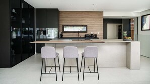 Eine moderne Küche mit einer zentralen Kochinsel, Barhocker und einem integrierten Backofen.