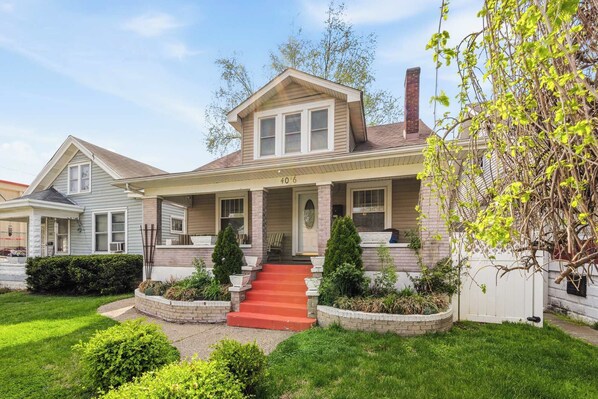 A two-story house with a front porch, a chimney, and a well-maintained lawn.