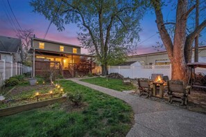 A residential property with a front porch, a fire pit, and a well-maintained garden.