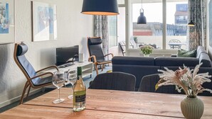 Un salon moderne comprenant un canapé, une table à manger, des chaises et un téléviseur.