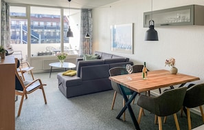 Ein modernes Wohnzimmer mit grauem Sofa, Esstisch aus Holz und Stühlen.