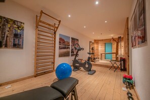 Ein Fitnessraum mit Trainingsgeräten, Holzboden und einem blauen Trainingsball.