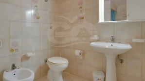 Baño con inodoro, bidé, lavabo y espejo.