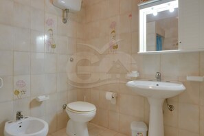 A bathroom with a toilet, bidet, sink, and mirror. - VILLA FLORA - Villa Flora - Mono 3 (Capoliveri)
