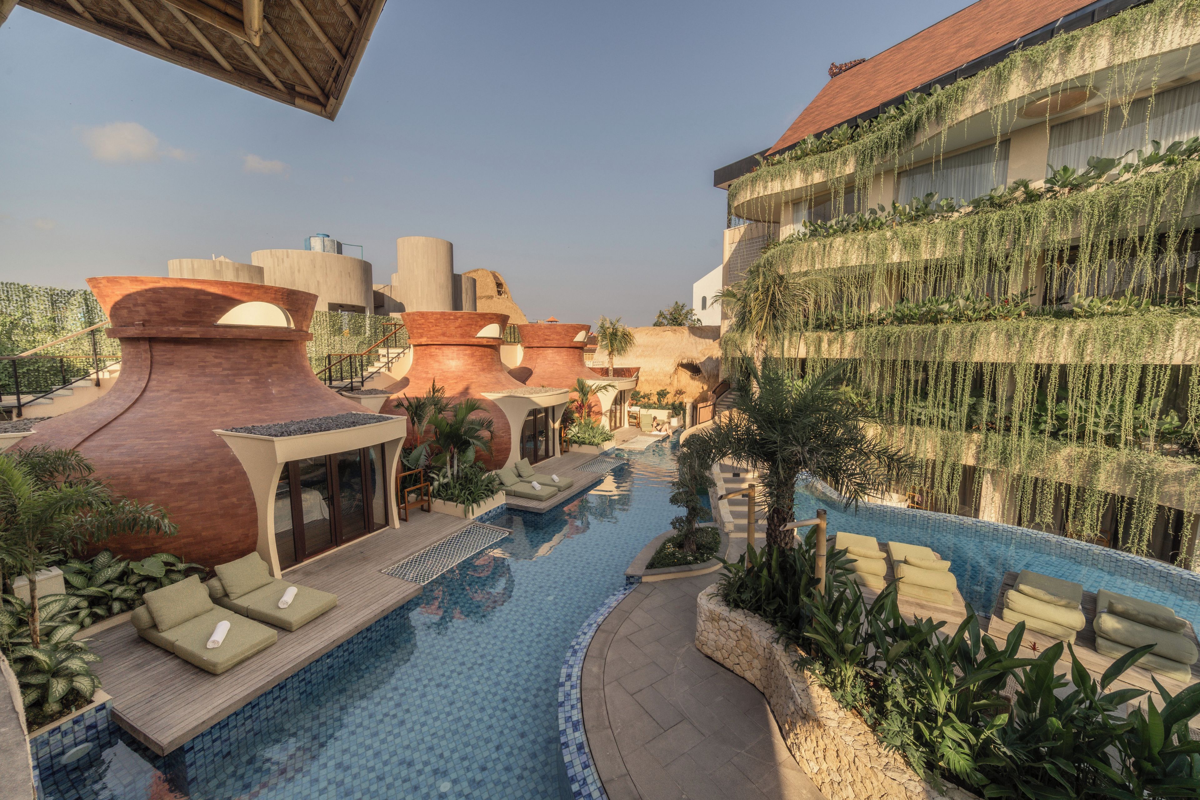 A resort with a swimming pool, lounge areas, and a building with a unique architectural design.