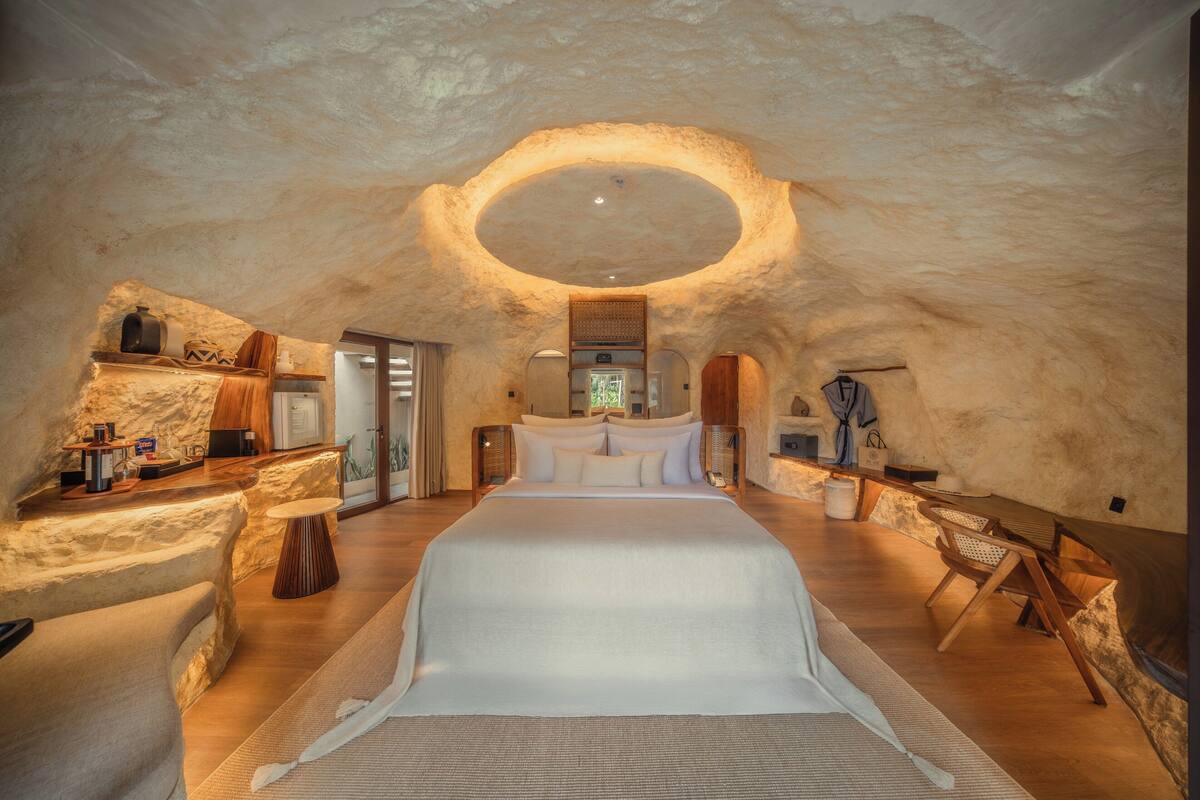 A spacious room with a large bed, wooden furniture, and a unique ceiling design.