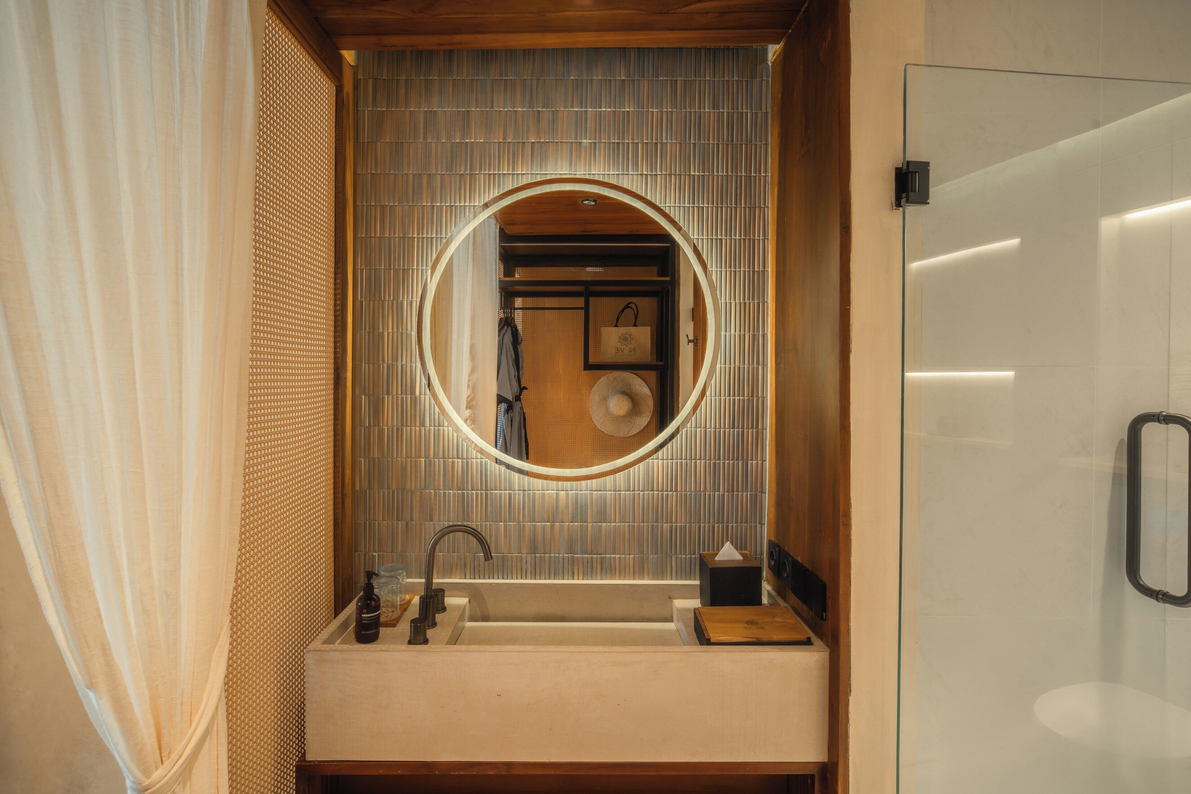 A bathroom with a round mirror, a sink, and a towel rack.