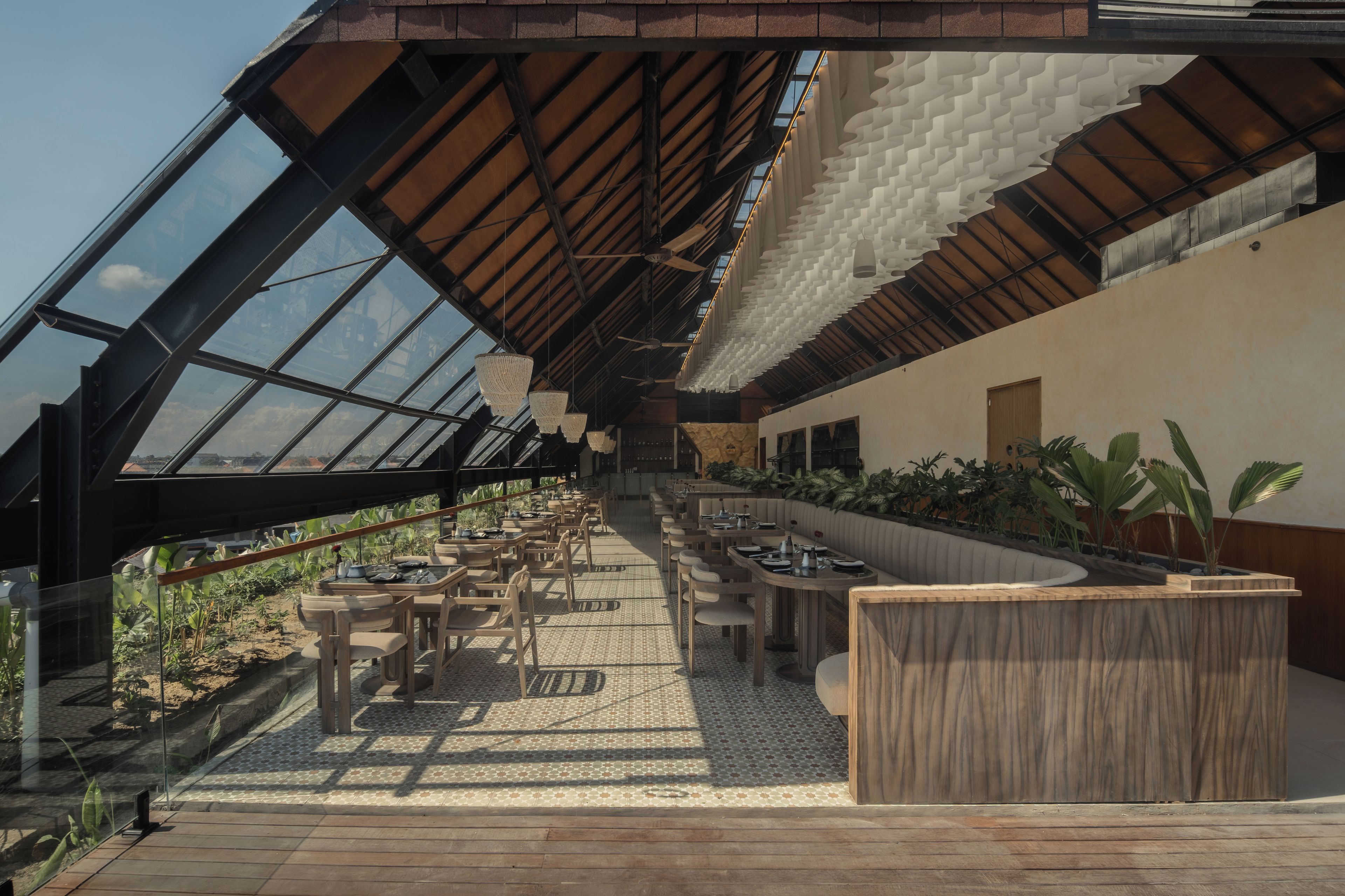 A modern interior with a long dining area, high ceilings, and a view through a glass roof.