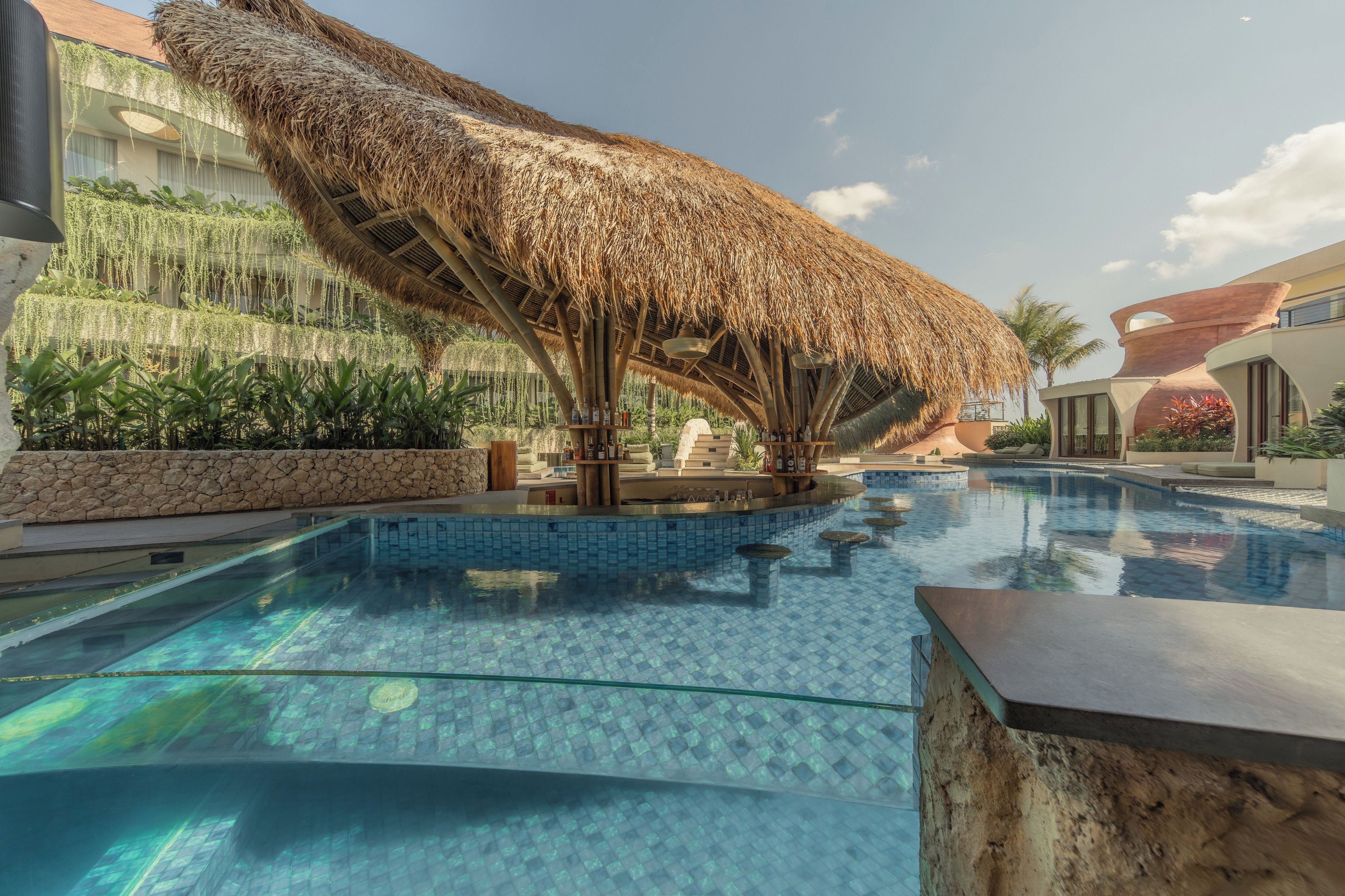 A swimming pool with a thatched structure and a stone wall.