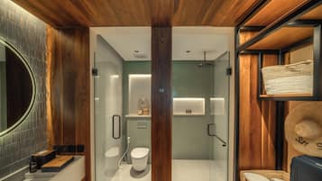 Et moderne badeværelse med træloft, brusekabine i glas, toilet og håndvask.