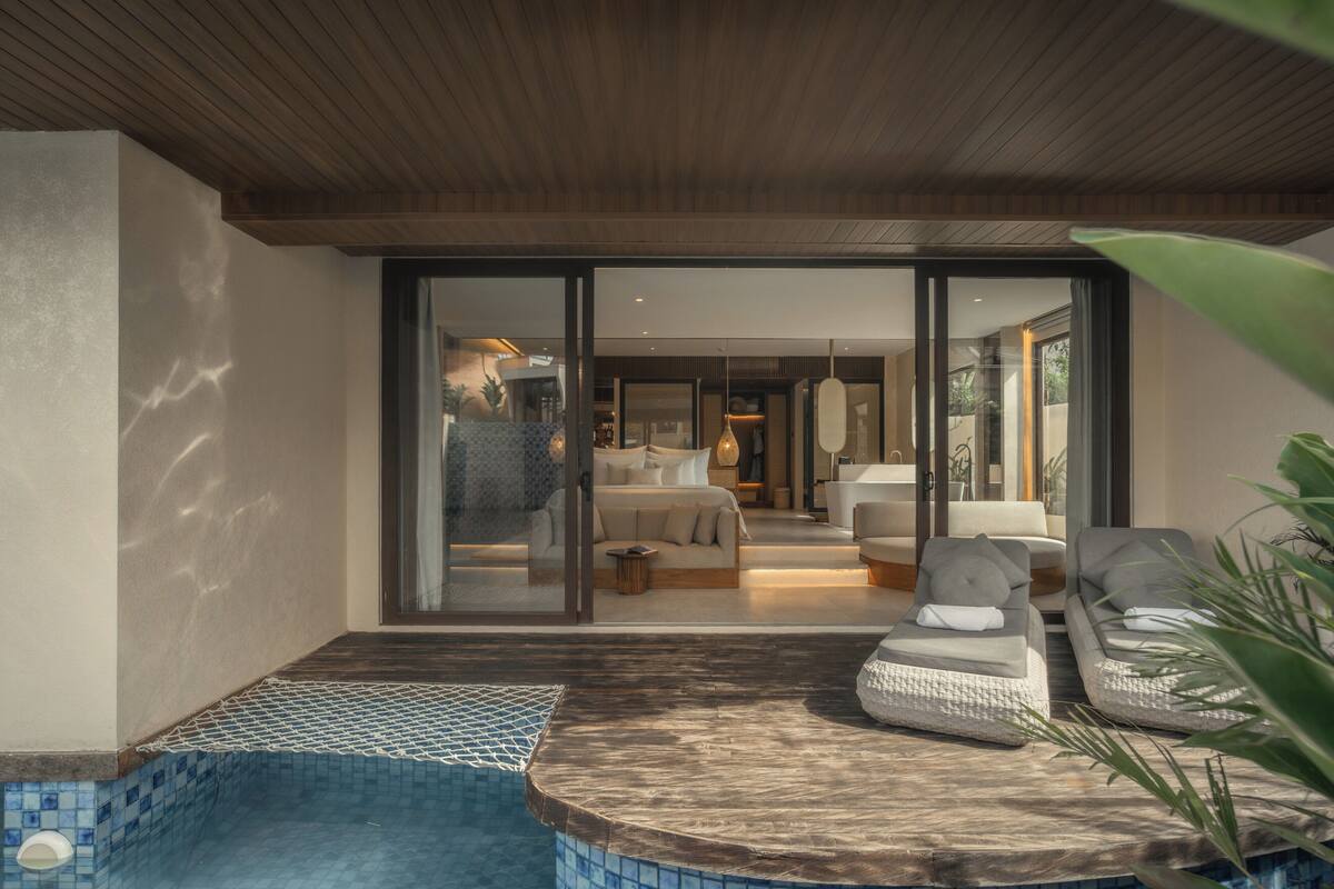 A modern pool area with a glass-enclosed bedroom visible through the glass doors.