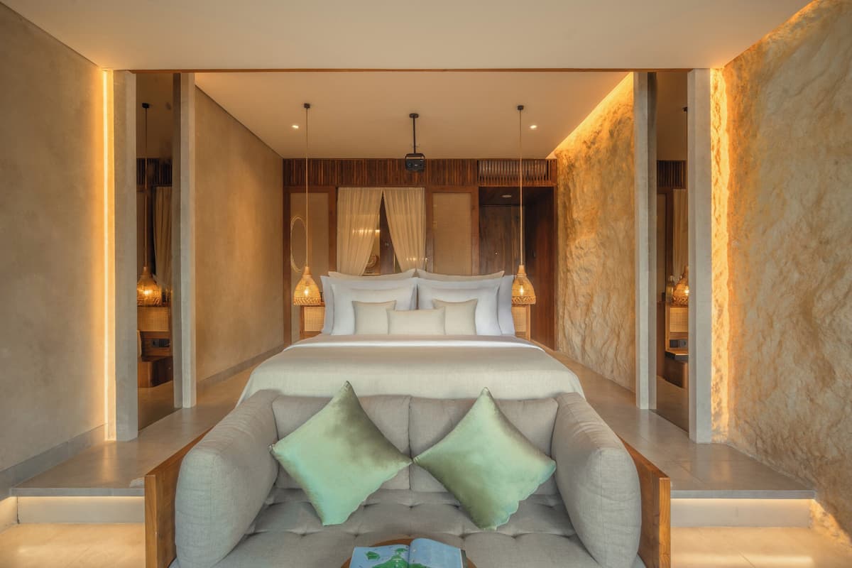 A modern bedroom with a large bed, a sofa, and a view of the room's interior.