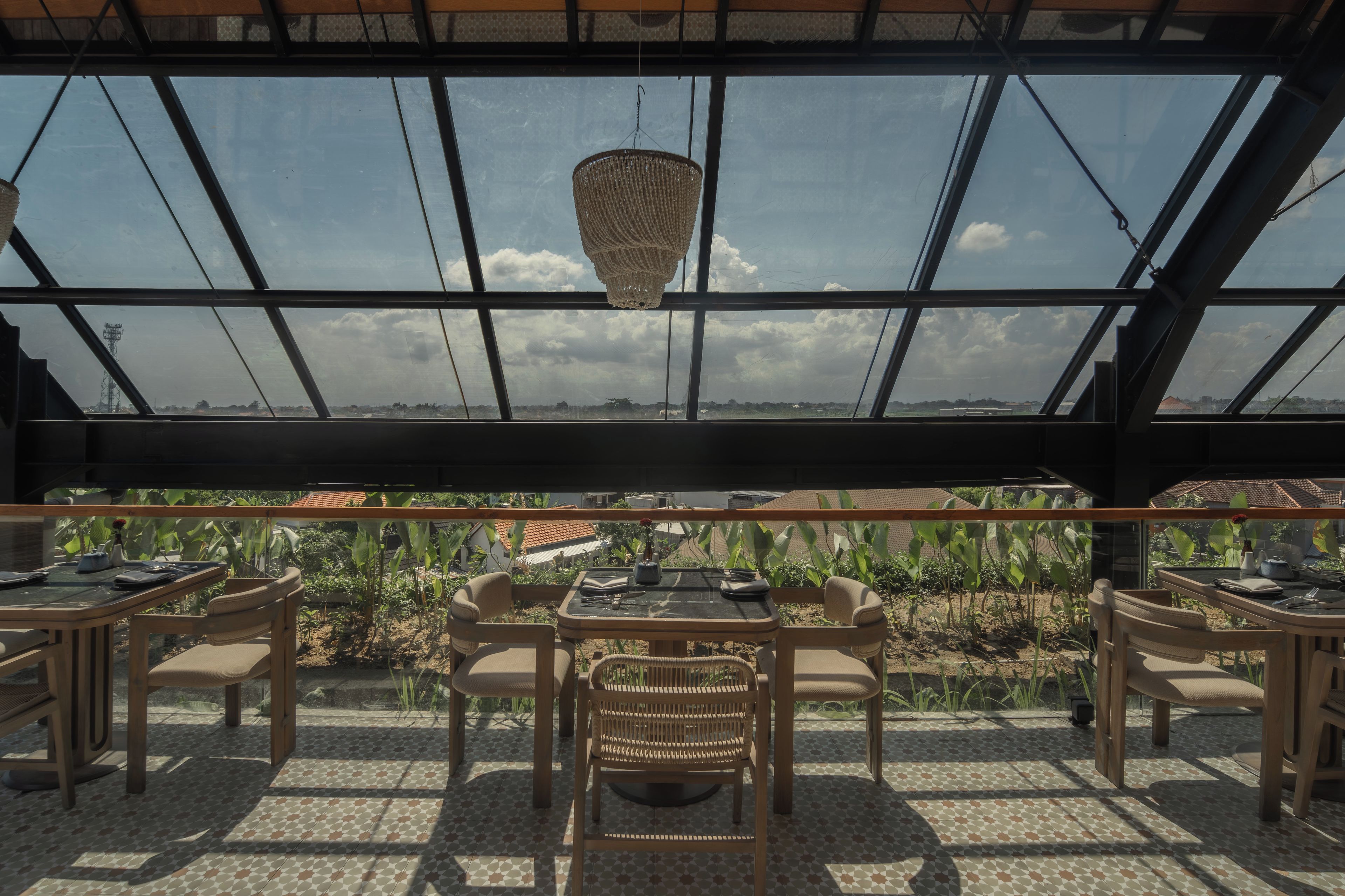 A restaurant with a large glass roof, outdoor seating, and a view of the landscape.