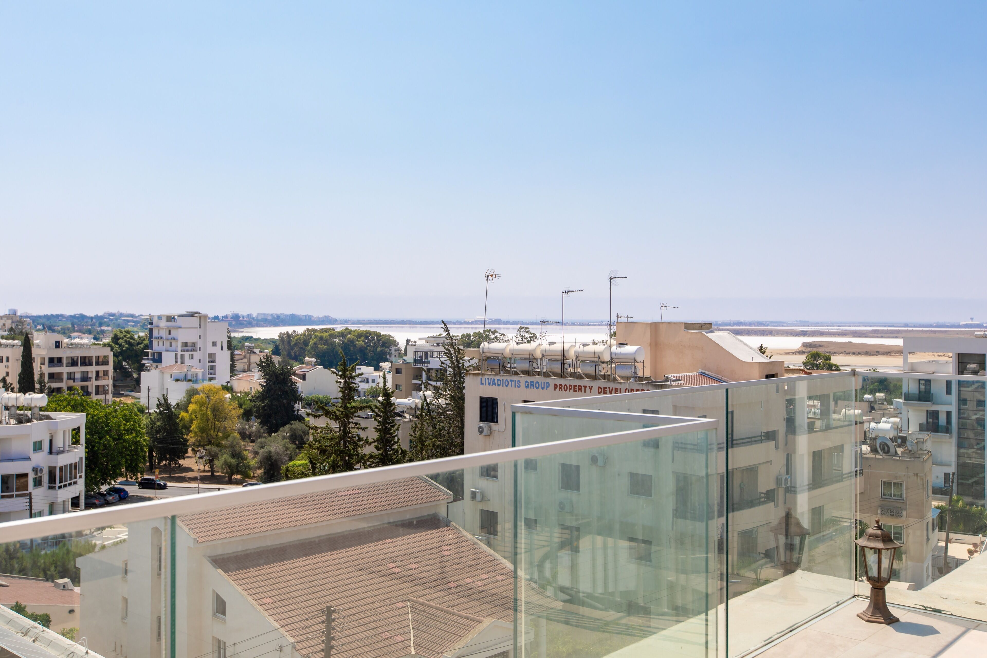 Un edificio moderno con fachada de vidrio, terraza en la azotea y vistas claras del paisaje urbano circundante.