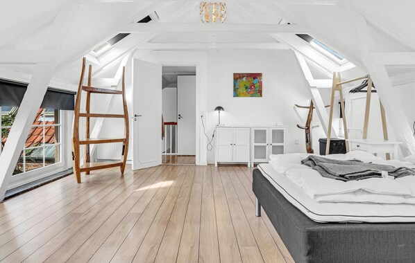 Amplio dormitorio tipo loft con suelo de madera, una cama, un escritorio y un cuadro en la pared.