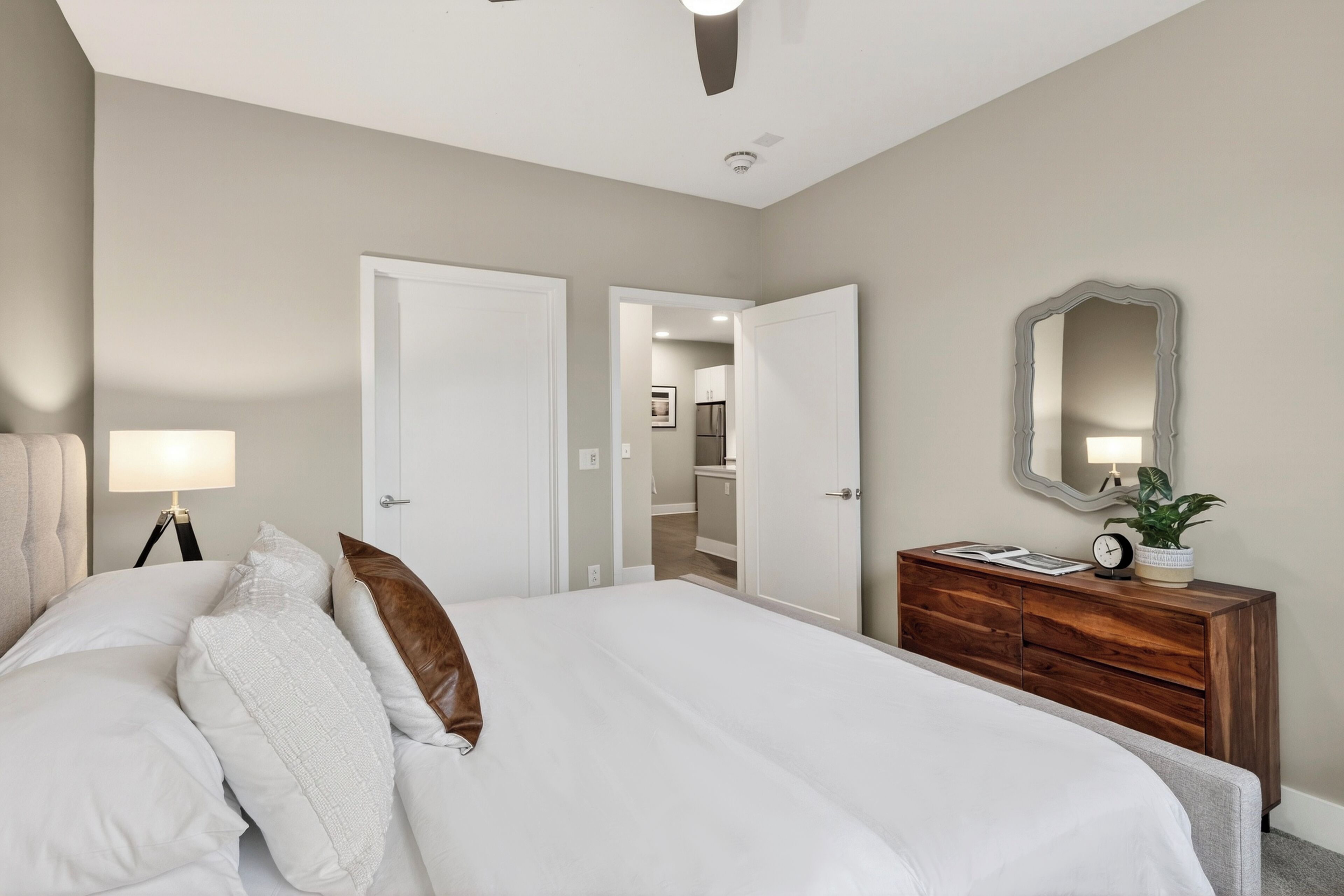 Een slaapkamer met een bed, bedlampje, kaptafel, spiegel en een open deur naar een badkamer.