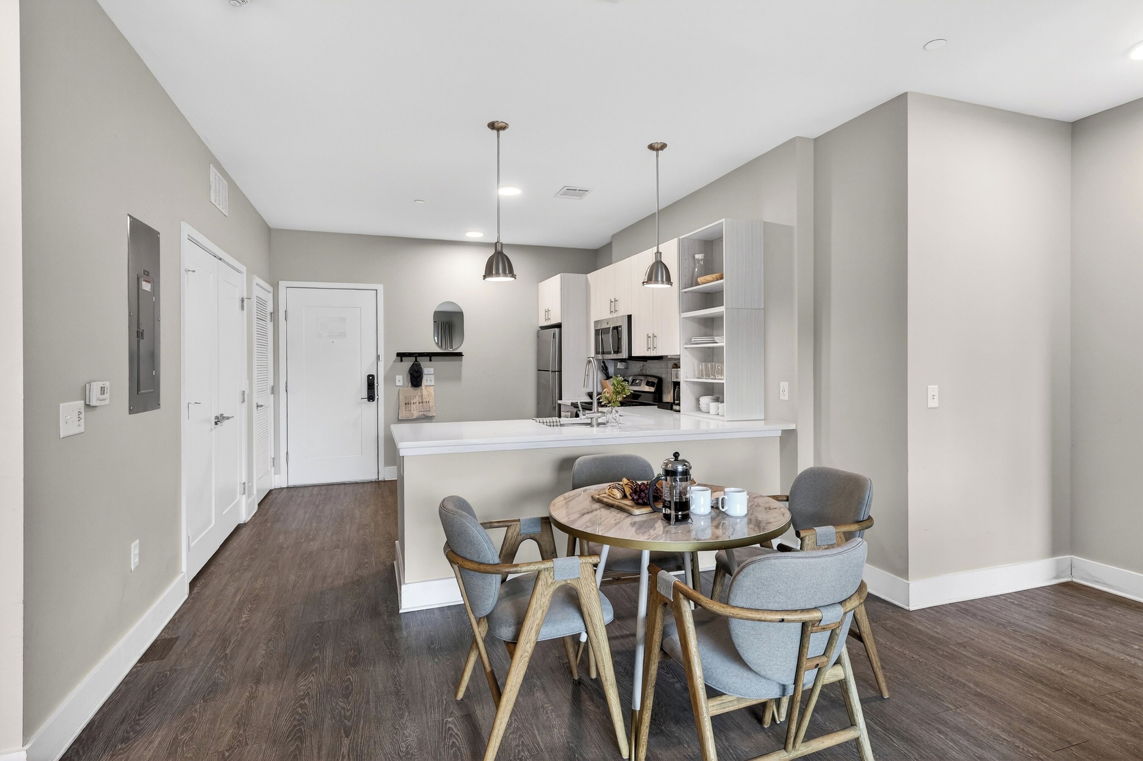 A modern kitchen with a central island, wooden chairs, and a dining table.