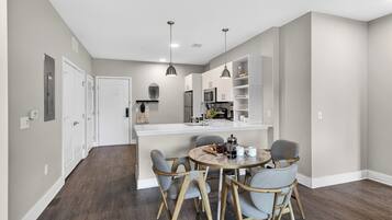 A modern kitchen with a central island, wooden chairs, and a dining table.
