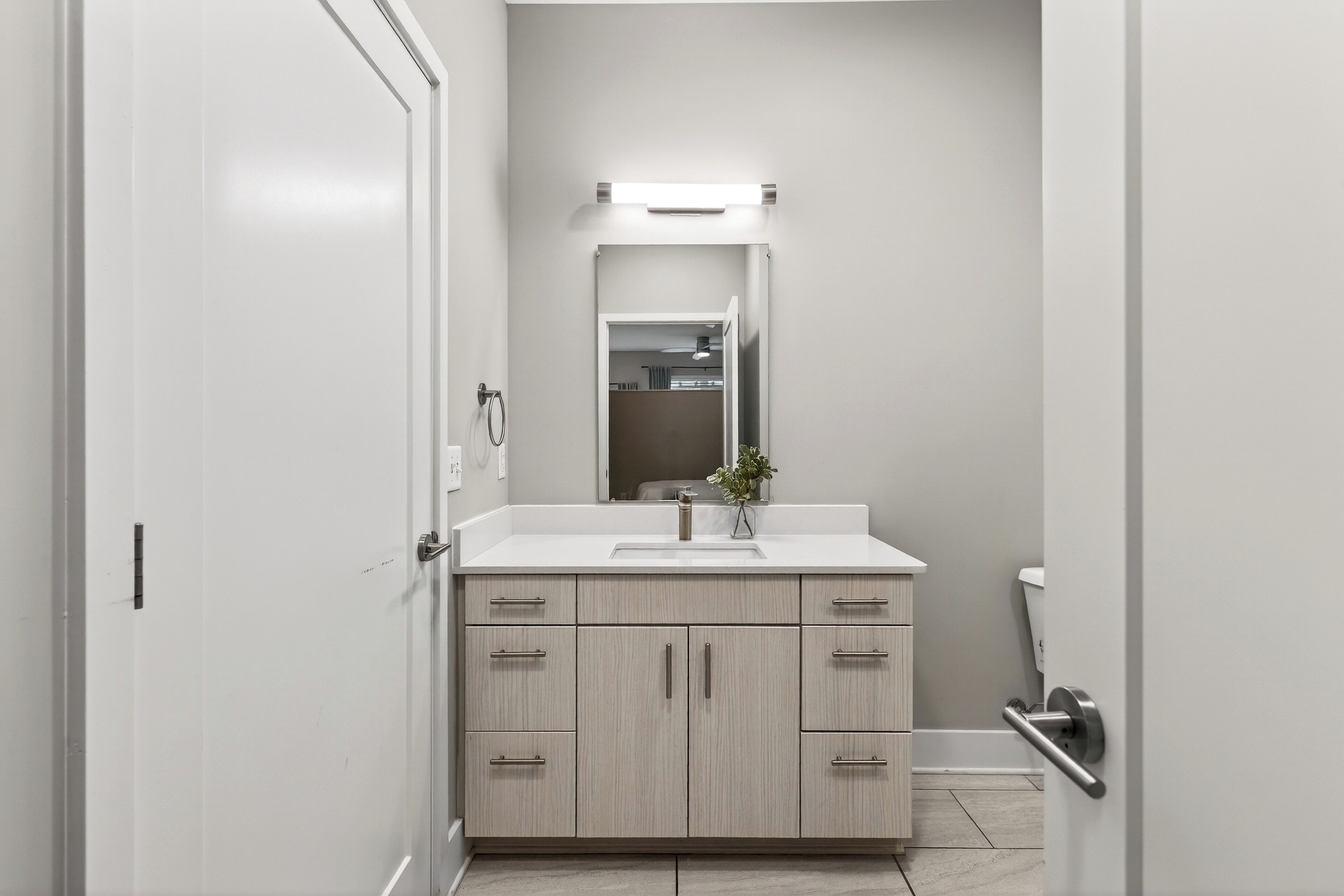 Une salle de bain moderne avec un meuble-lavabo blanc, un miroir et des toilettes.