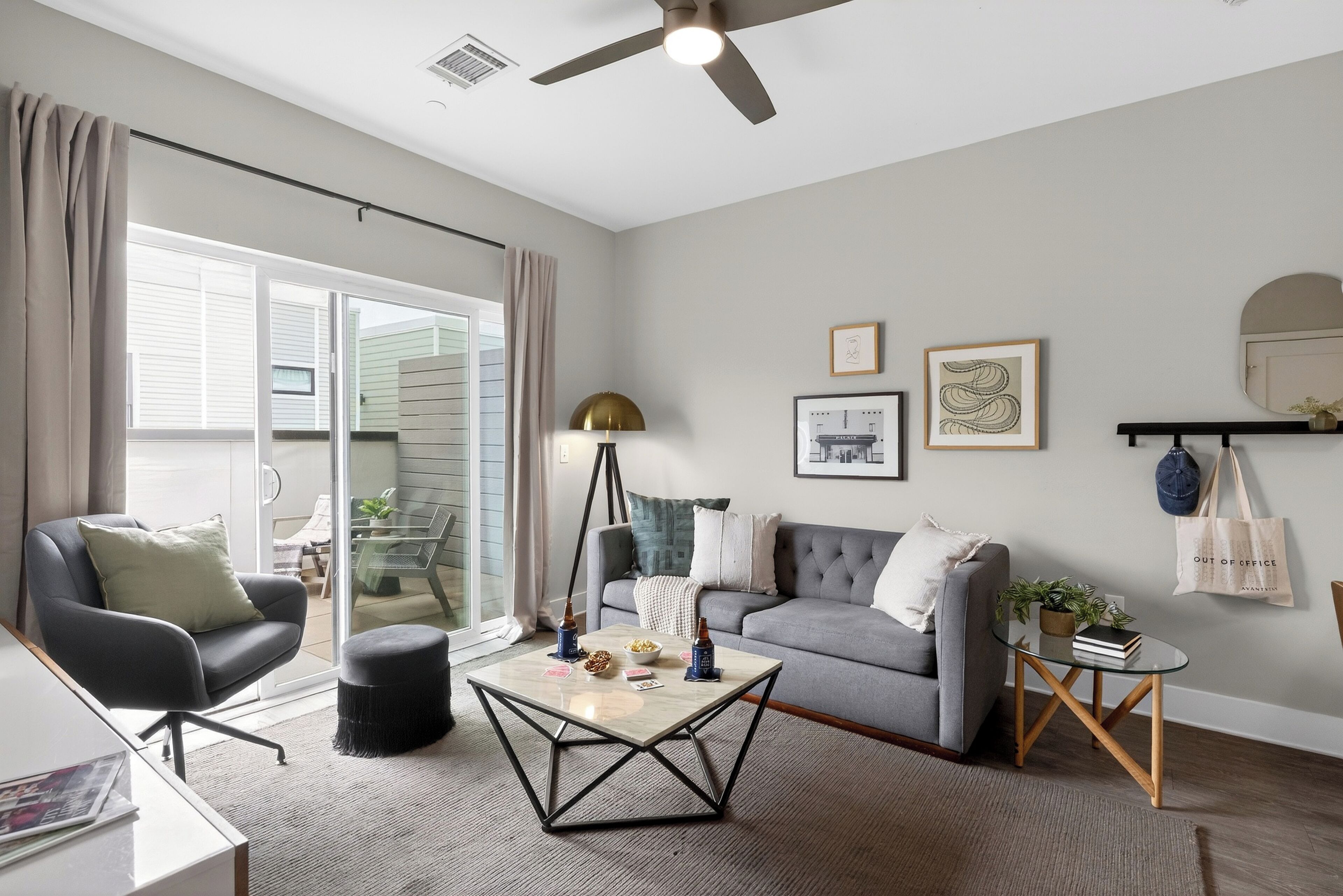 A living room with a sofa, a coffee table, a lamp, and a sliding glass door leading to an outdoor area.