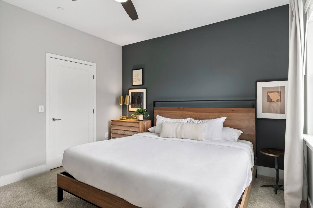 A bedroom with a bed, bedside table, lamp, and wall art.