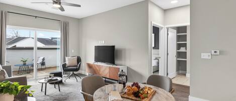 Una sala de estar moderna con una mesa redonda para comer, un televisor de pantalla plana y un balcón con vistas.