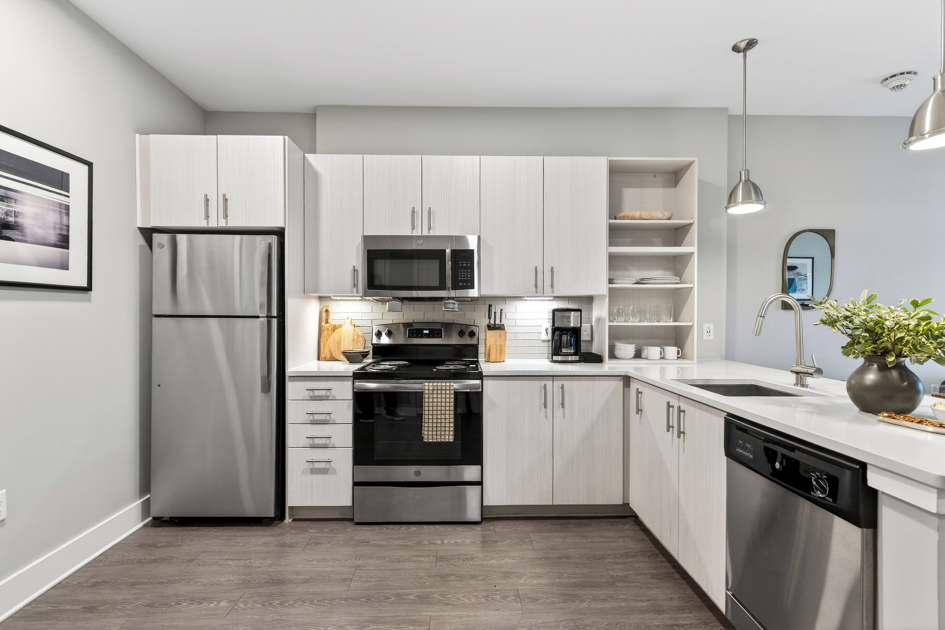 A modern kitchen with stainless steel appliances, white cabinetry, and a built-in oven.