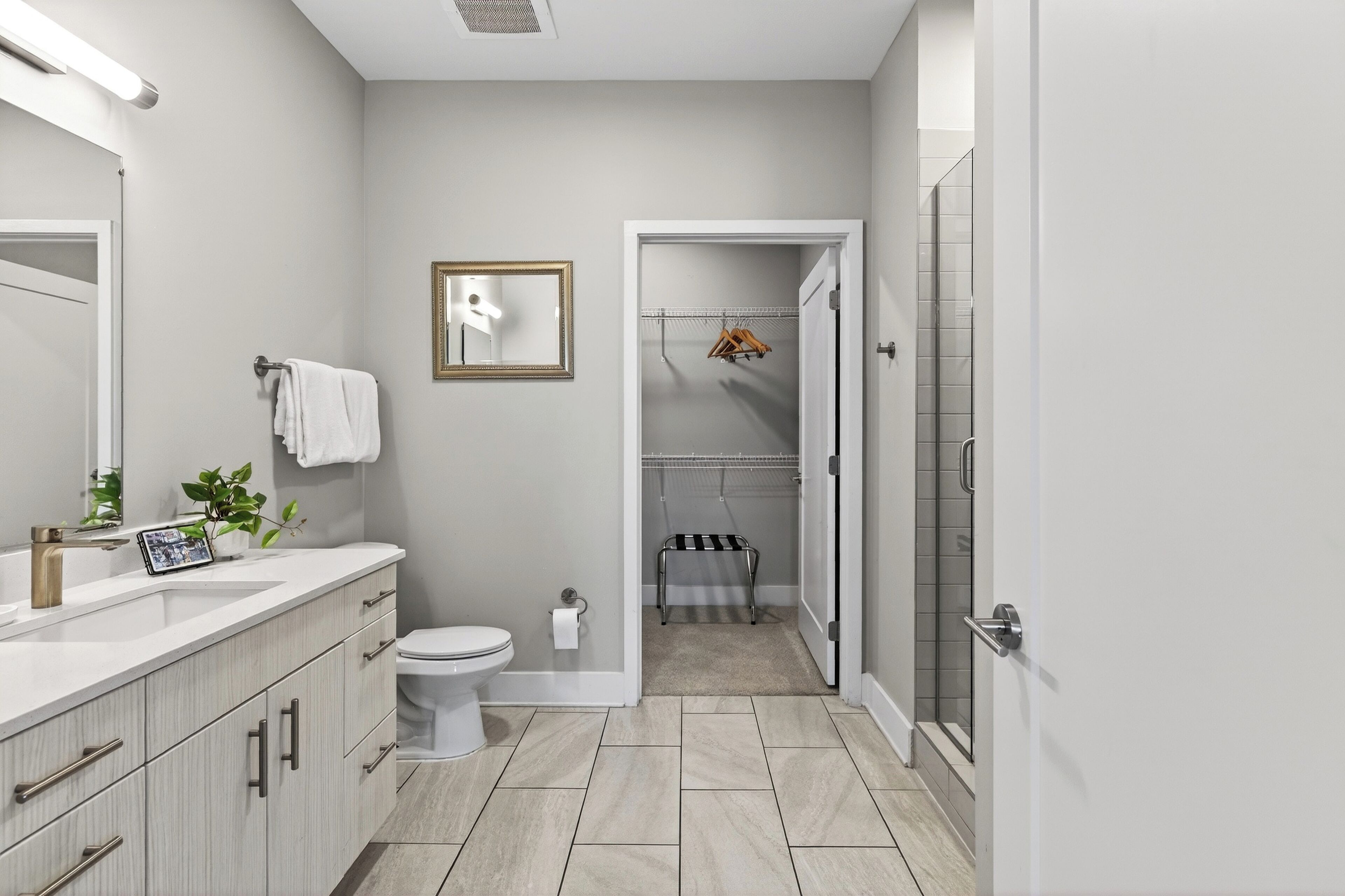 A modern bathroom with a toilet, sink, mirror, and shower area.