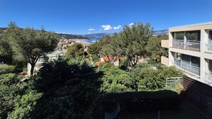 Un quartier résidentiel situé sur la côte, offrant une vue sur la mer, des arbres et un immeuble moderne doté de balcons.
