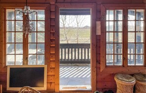 A wooden cabin interior with large windows, a chandelier, and a view of a wooden deck outside. - Gorgeous home in Væggerløse with WiFi (Væggerløse)