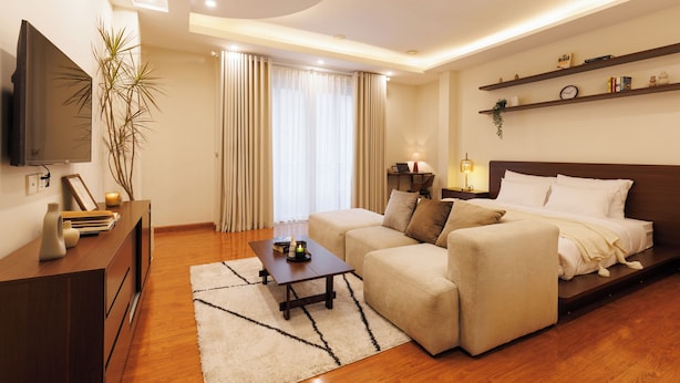 A modern living room with a sofa, a coffee table, a TV, and a bookshelf. - Beloved Summer - 4BR Cozy & Peaceful with Elevator (Hà Nội)