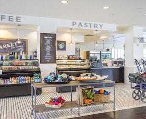 Un café qui propose également une épicerie et une sélection de pâtisseries, avec un comptoir où sont exposés divers produits et un présentoir de boissons.