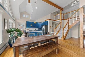 Eine geräumige Küche mit blauen Schränken, einem Holzespeisesaal und einer Treppe mit Holzgeländern.