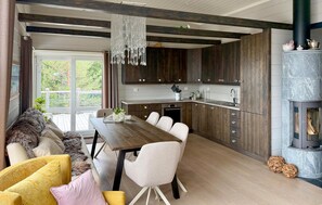 A modern kitchen with dark wooden cabinets, a central island, and a stone fireplace. - Awesome home in Stryn with house a mountain view (Stryn)