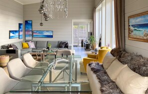 A modern living room with a glass coffee table, a sofa, a yellow armchair, and a painting of a beach scene. - Awesome home in Stryn with house a mountain view (Stryn)