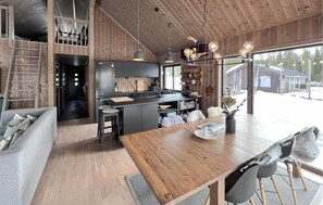 Eine moderne Küche mit Holzakzenten, ein Essbereich mit Holztisch und Blick ins Freie.