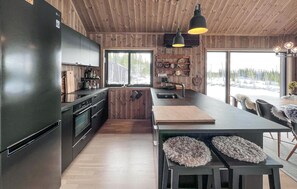 Eine moderne Küche mit Holzwänden, einer großen Kochinsel und Blick auf eine verschneite Landschaft.