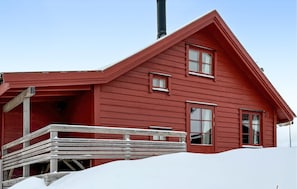 Ein rotes Holzhaus mit Veranda und Schornstein.