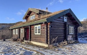 A log cabin with a sloped roof, a front porch, and a chimney.