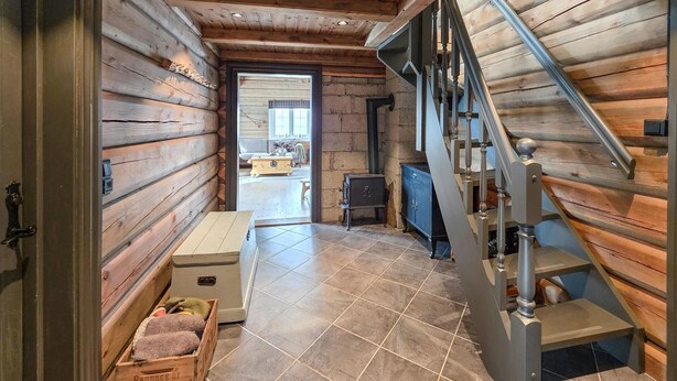 A log cabin interior with a staircase, a fireplace, and a view into the living area. - Amazing home in Ustaoset (Ustaoset)