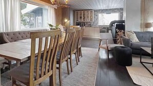 Un espace repas avec une table et des chaises en bois, un canapé et, au fond, une cuisine.