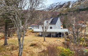A house with a porch, surrounded by trees and a mountain in the background.