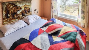Un letto con una coperta colorata, un muro decorato e una finestra con tende.