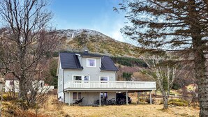 Una casa a due piani con un balcone, un garage e una montagna sullo sfondo.