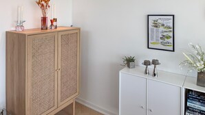 Een kamer met een houten kast, een witte bijzettafel en een inlijste kaart aan de muur.