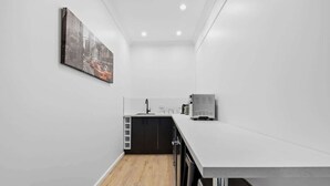 Una cocina moderna con encimera blanca, armarios negros y suelo de madera.