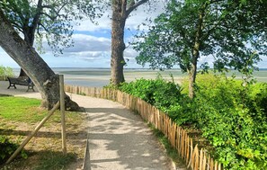 Ein Weg, der zu einem Strand mit Holzfence und Bänken führt.