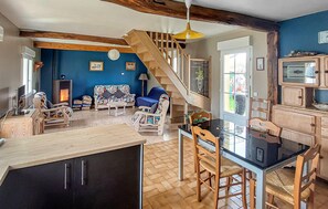 A spacious living area with a wooden staircase, a dining table with chairs, and a kitchen area with cabinets. - 2 bedroom cozy home in Saigneville (Saigneville)