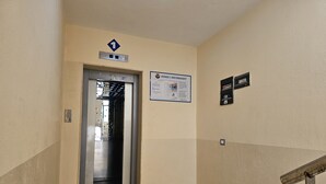 Un couloir avec un ascenseur, un panneau indicateur et un escalier.