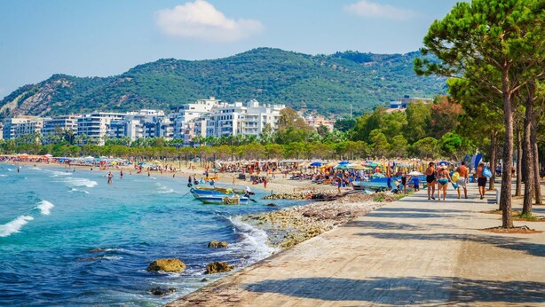 Une plage avec des gens, des bateaux et des bâtiments en arrière-plan.